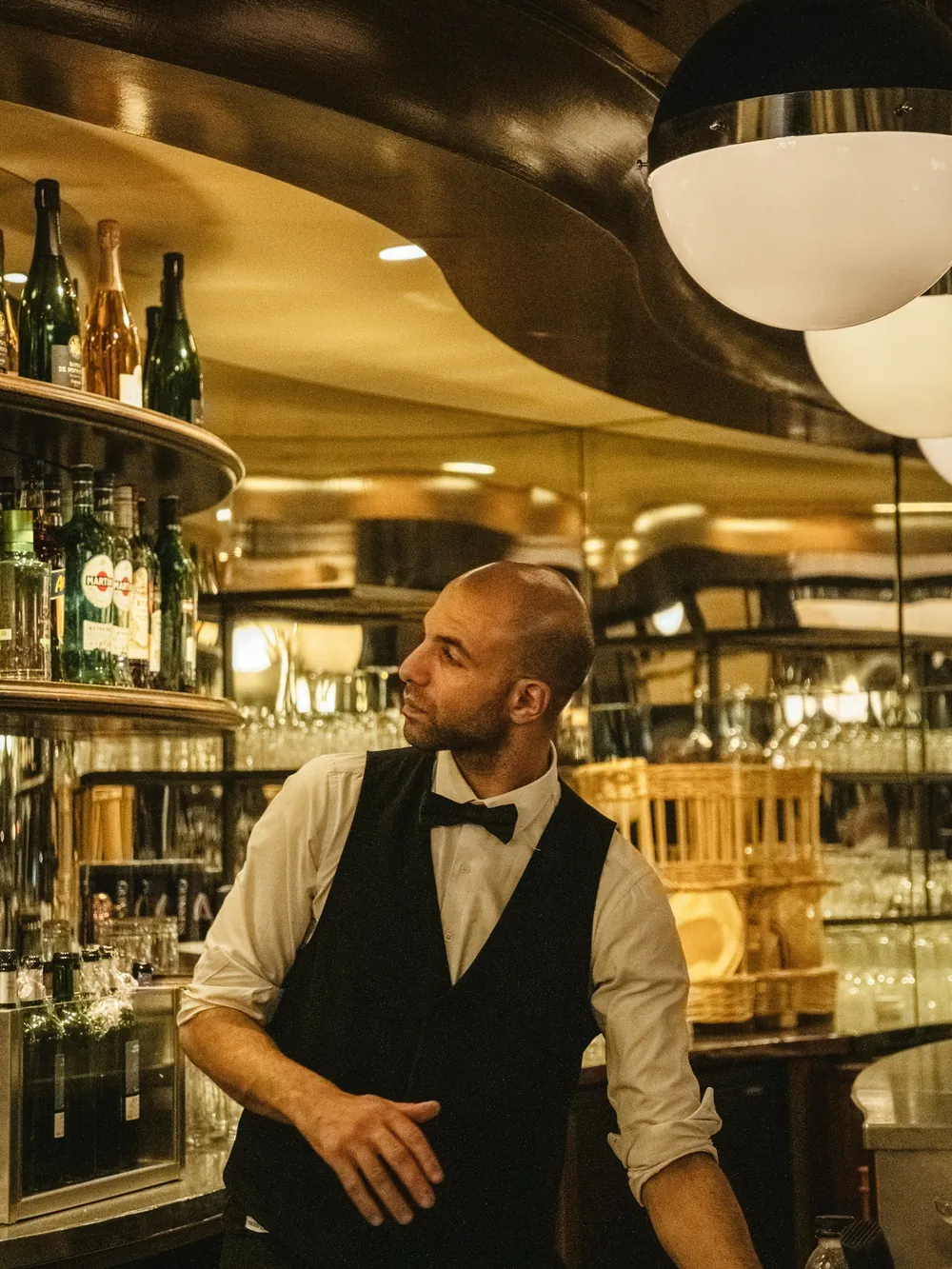 Le patron derrière le comptoir de la brasserie, devant les étagères de bouteilles